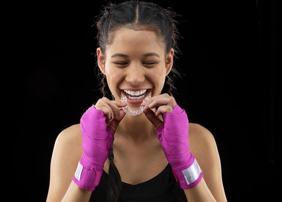 teen athlete holding Invisalign aligner